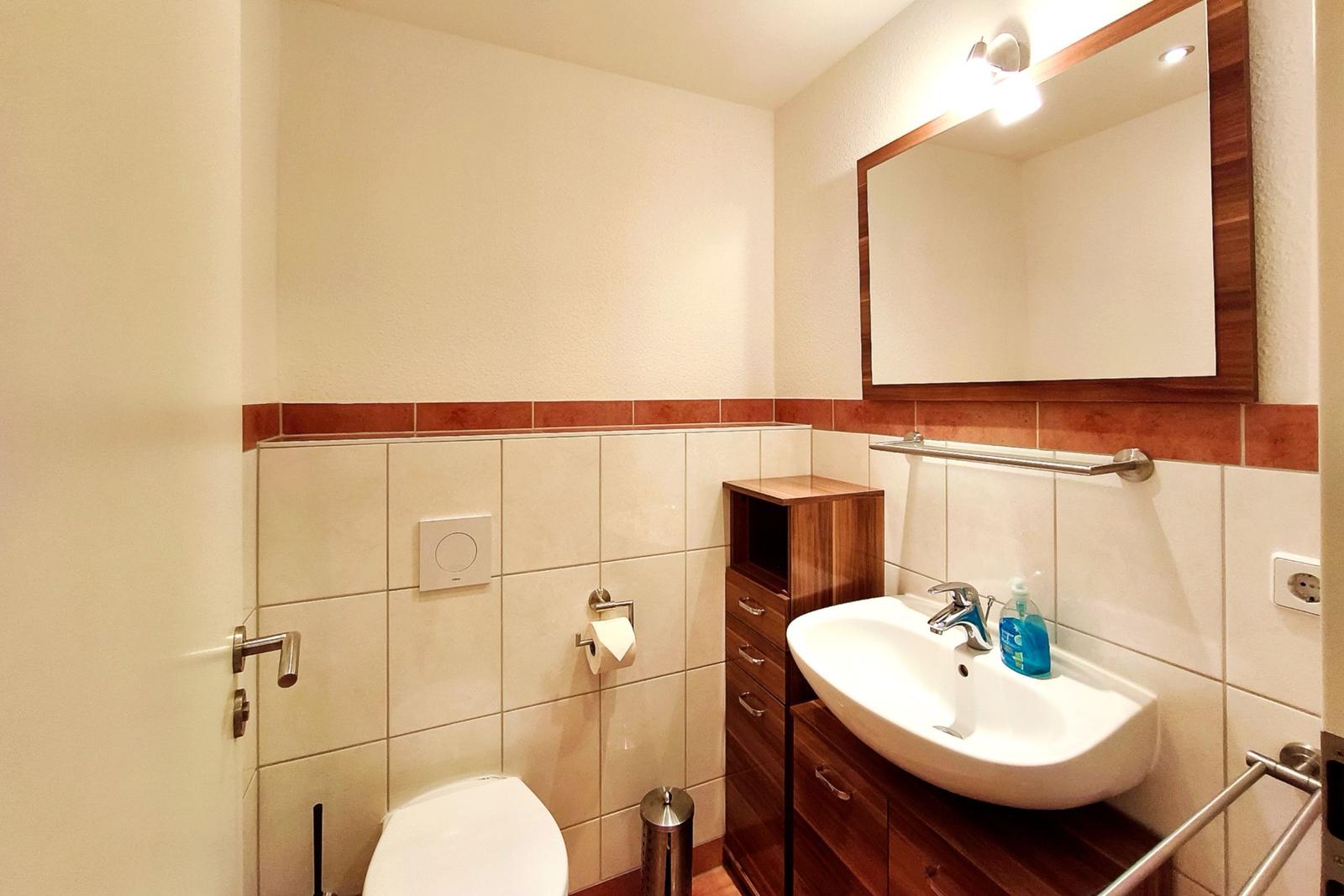 Separates Gäste-WC mit Handwaschbecken und Spiegel für zusätzlichen Komfort