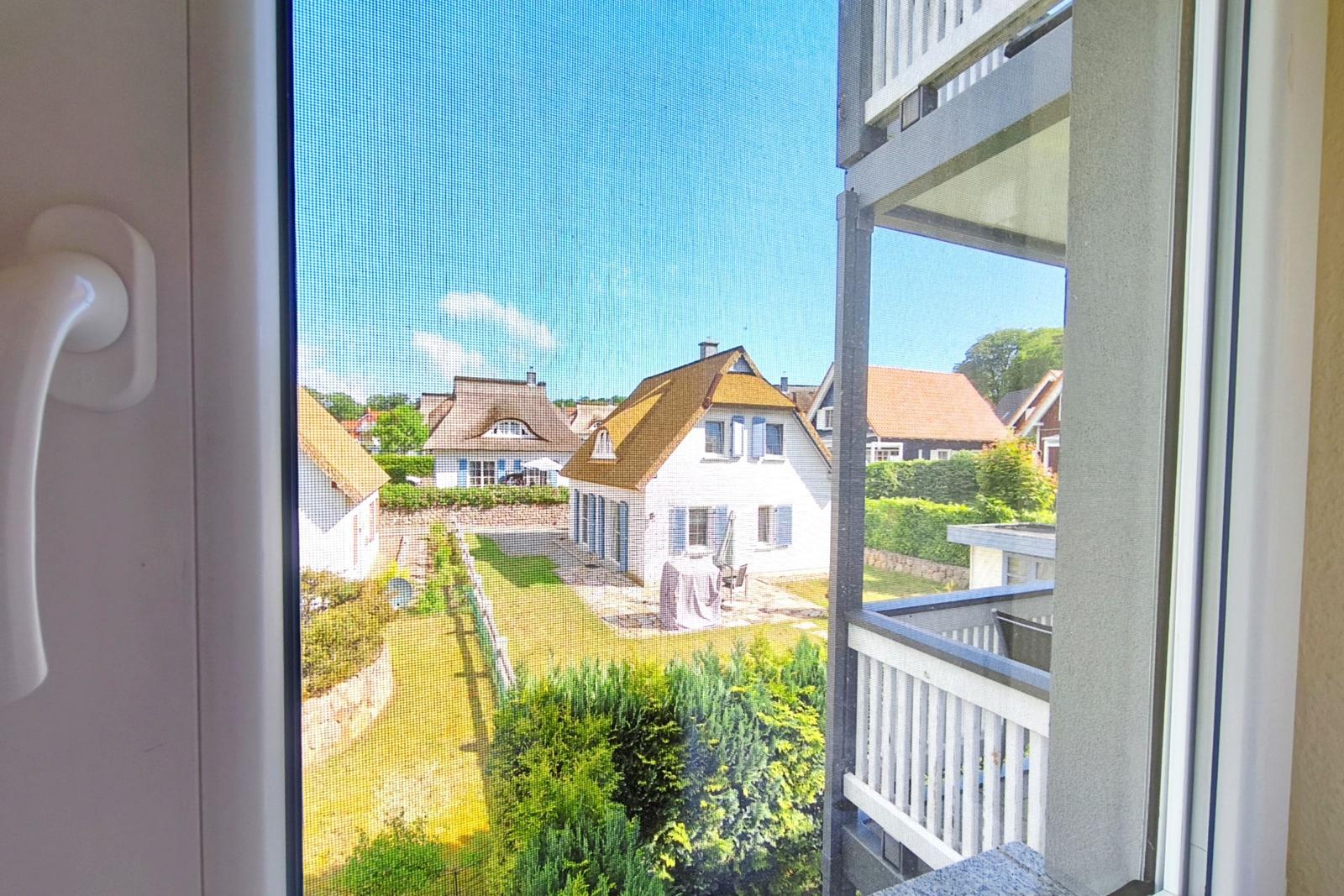 Geöffnetes Fenster mit Blick auf die gepflegten Nachbarhäuser der Ferienanlage