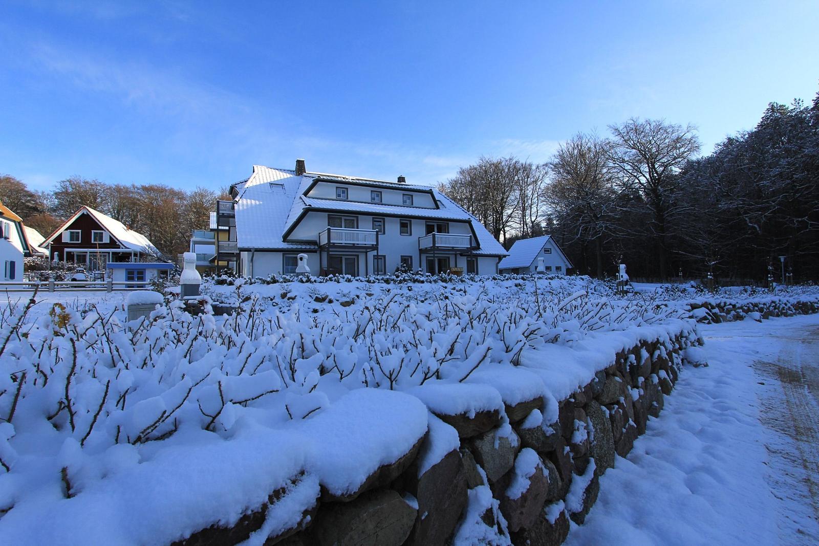 Romantische Winteransicht des verschneiten Ferienhauses unter blauem Himmel