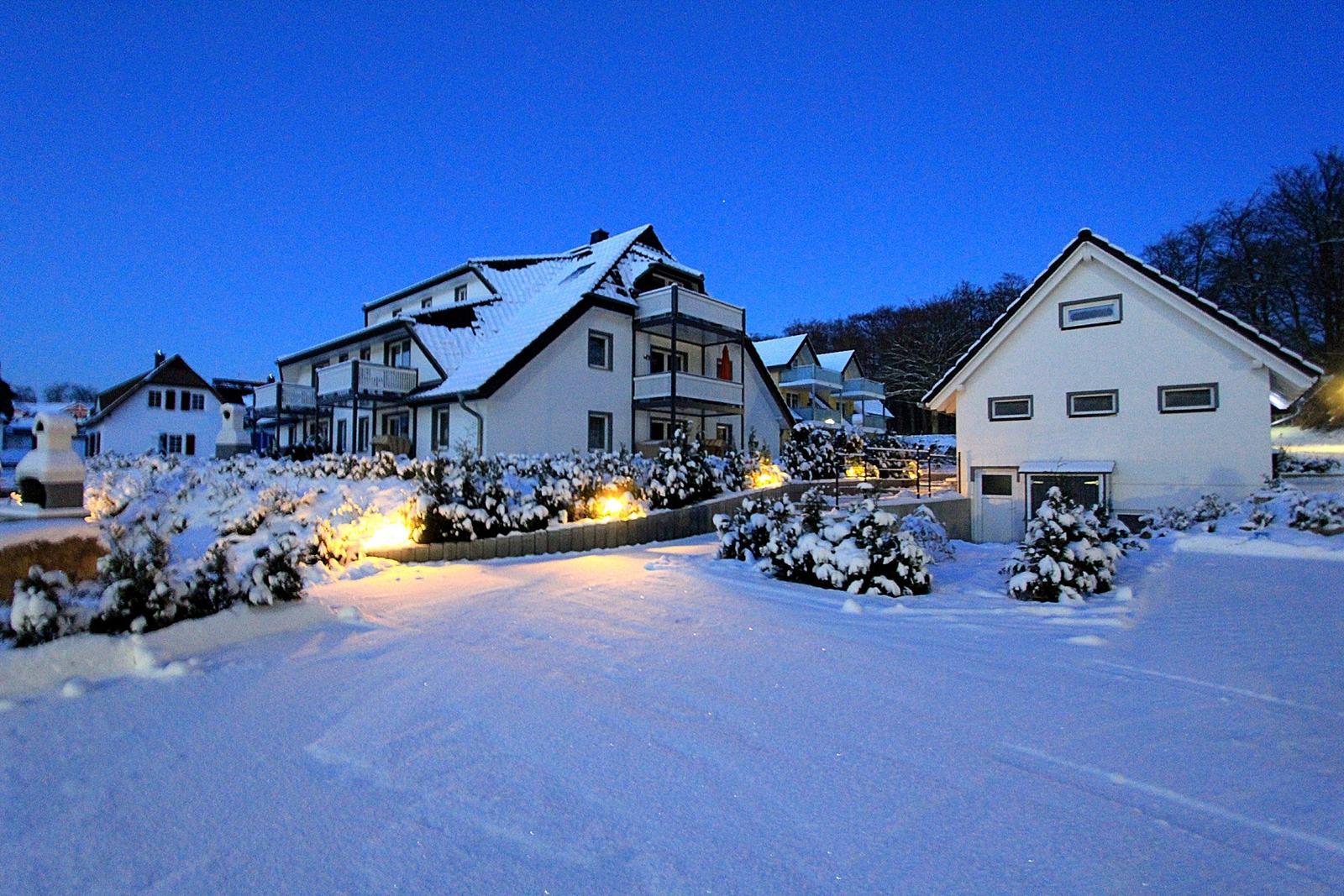 Verschneite Außenanlage mit stimmungsvoller Beleuchtung in der Abenddämmerung