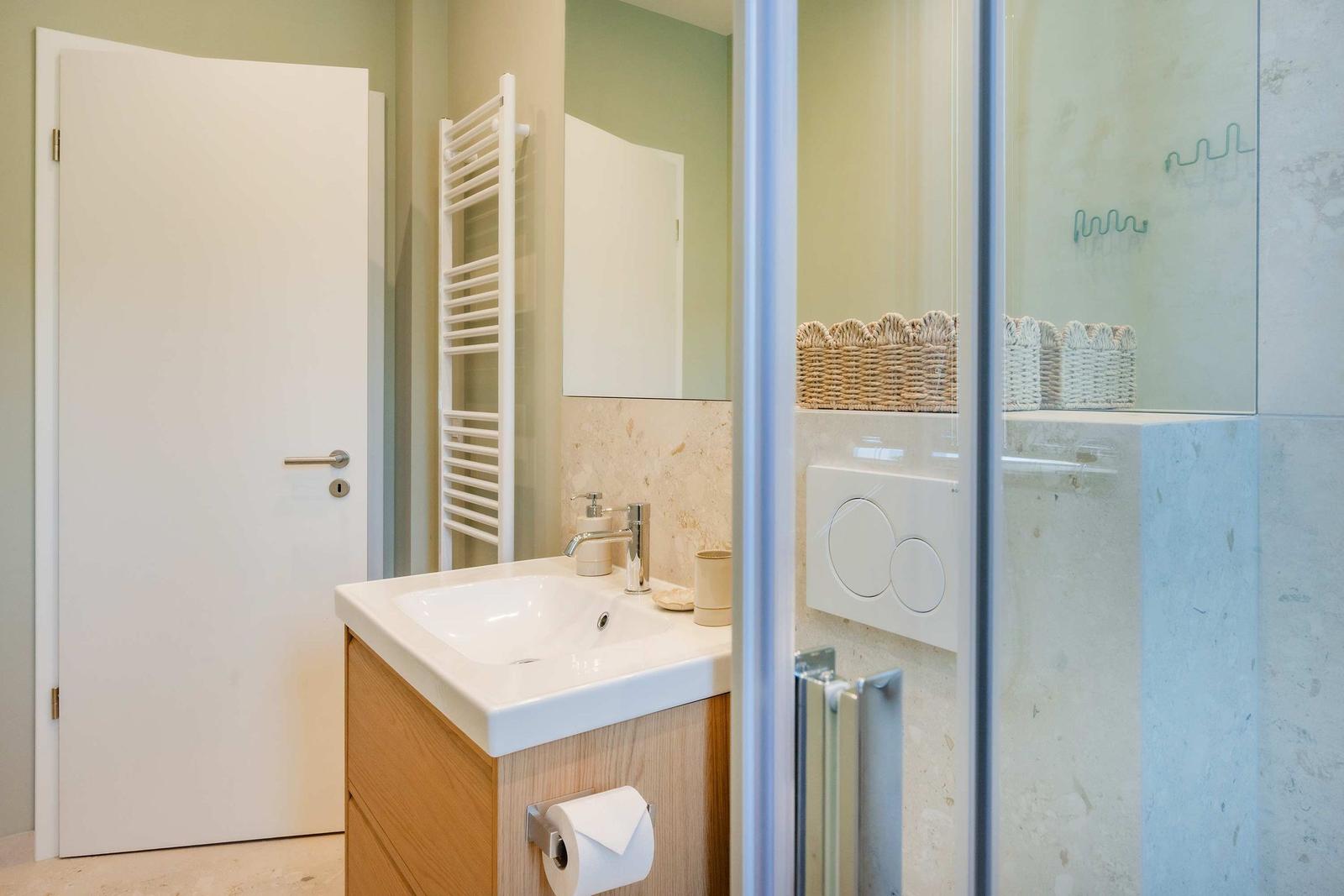 Badezimmer mit Waschbecken, Dusche und Heizkörper