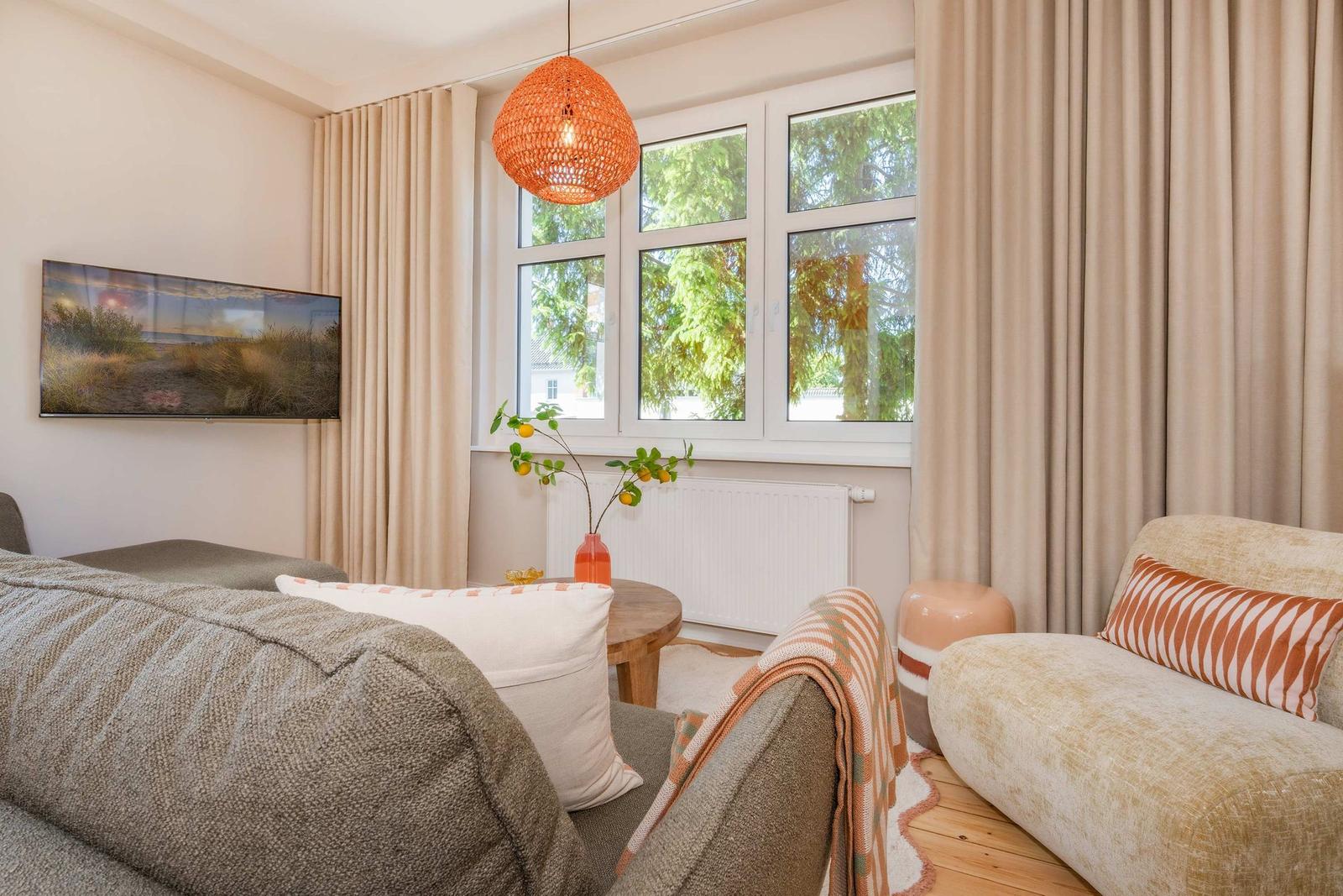 Wohnzimmer mit Sofa, Fenster und Deckenleuchte