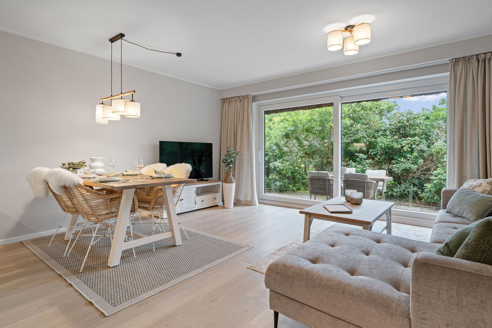 Wohn- und Essbereich mit großem Fenster, Tisch mit Stühlen und Sofa.