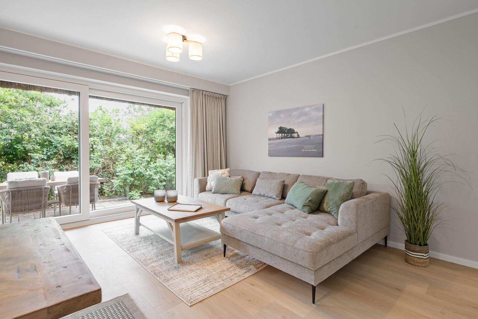 Wohnzimmer mit Sofa, Couchtisch und Glasfront zum Garten.