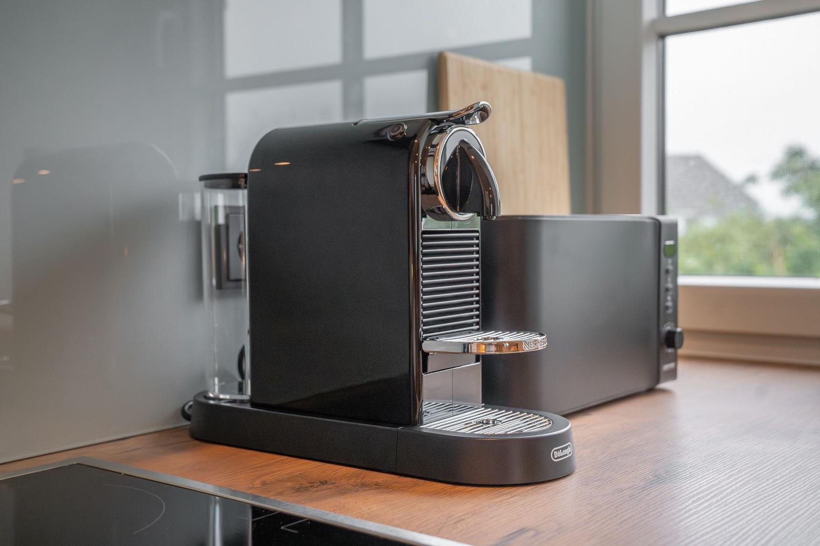 Küche mit schwarzer Nespresso-Kaffeemaschine und Mikrowelle auf Holzoberfläche.