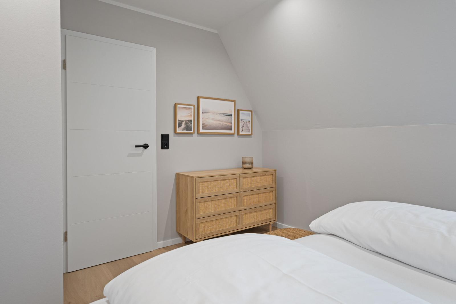 Schlafzimmer mit Bett, Schrank und Wandbildern