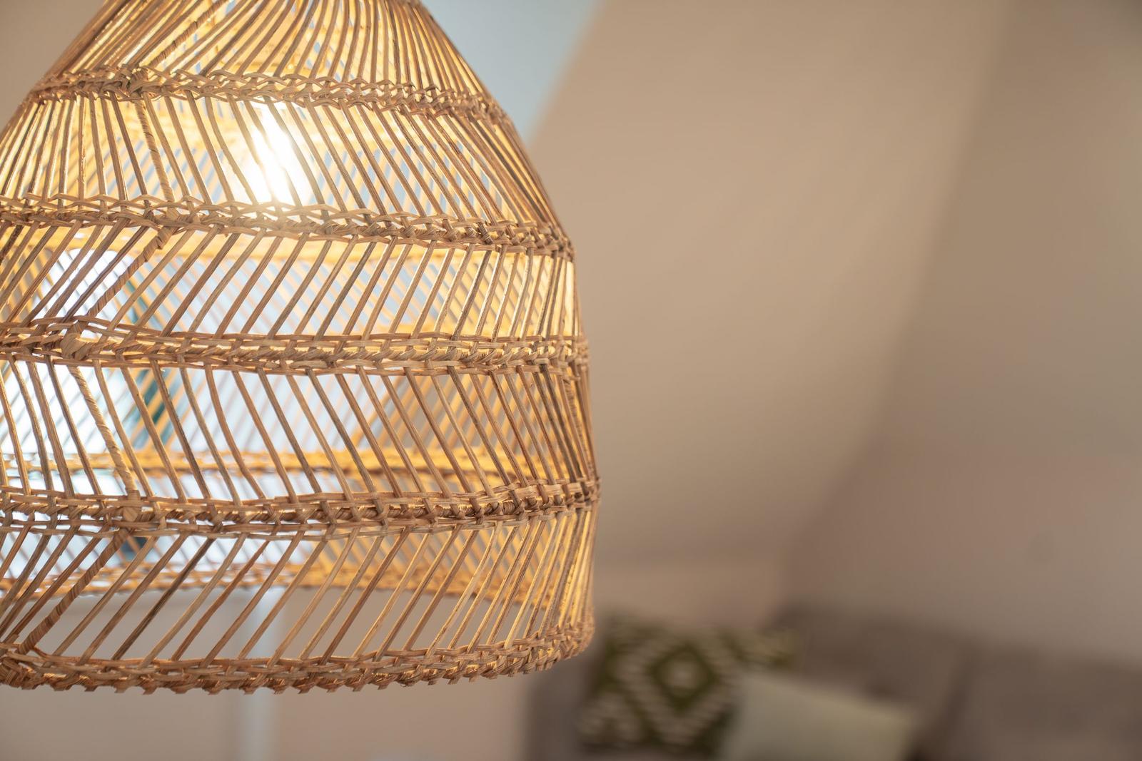 Hängelampe aus geflochtenem Rattan mit warmem Licht im Wohnbereich.