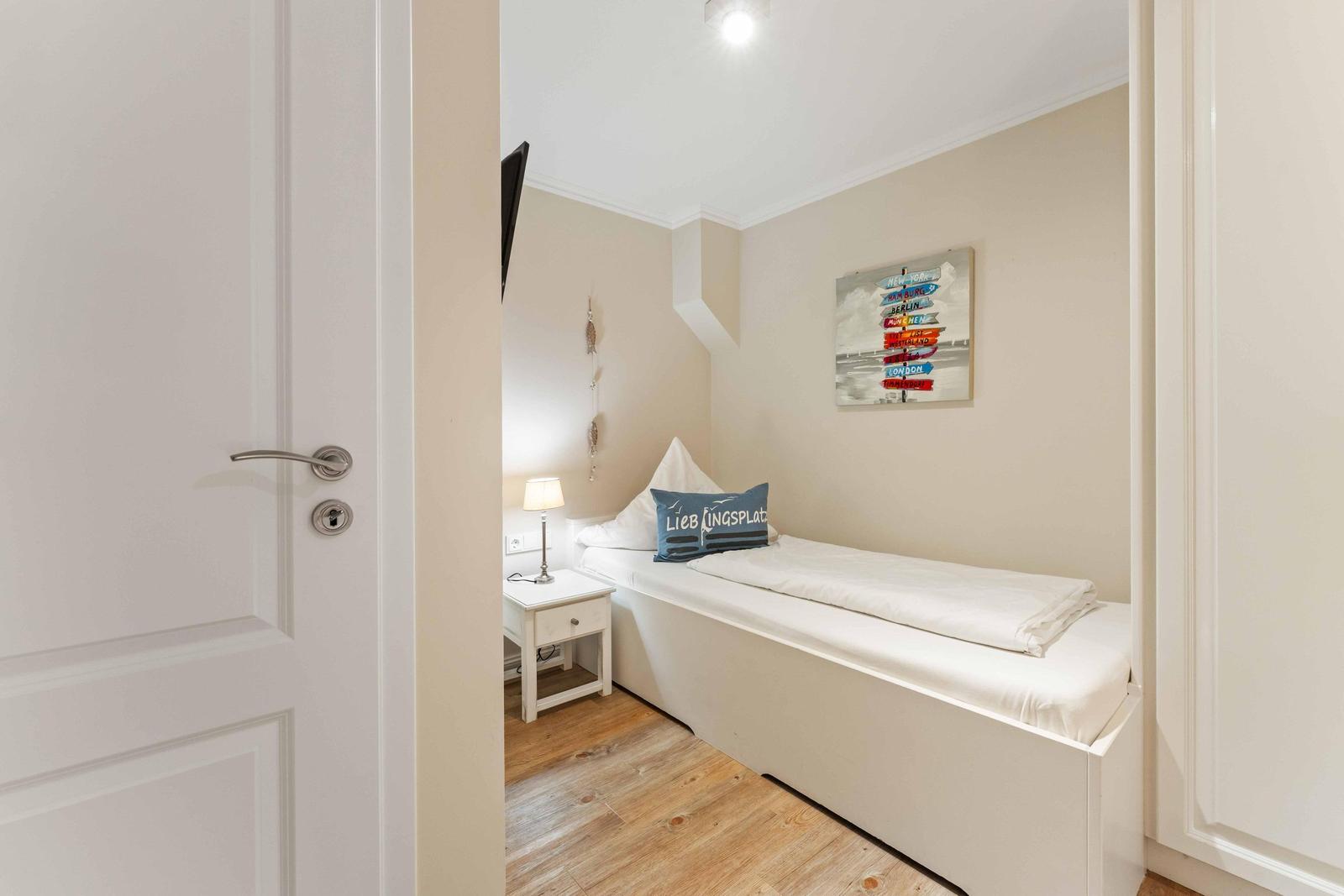 Schlafzimmer mit Einzelbett, Nachttisch und Wandbild.