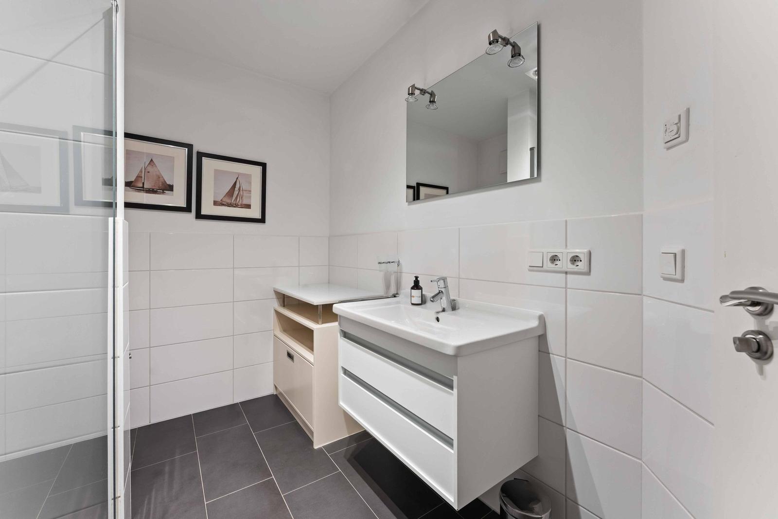 Bathroom with shower, sink, and mirror on the wall.