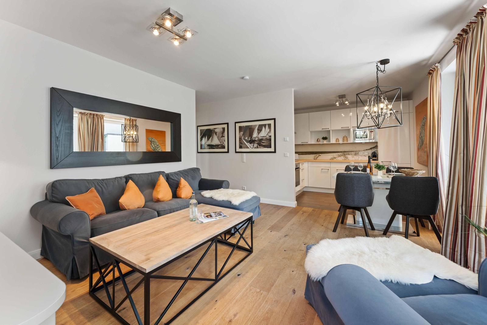 Living and dining area with sofa, coffee table, and kitchen area in the background.