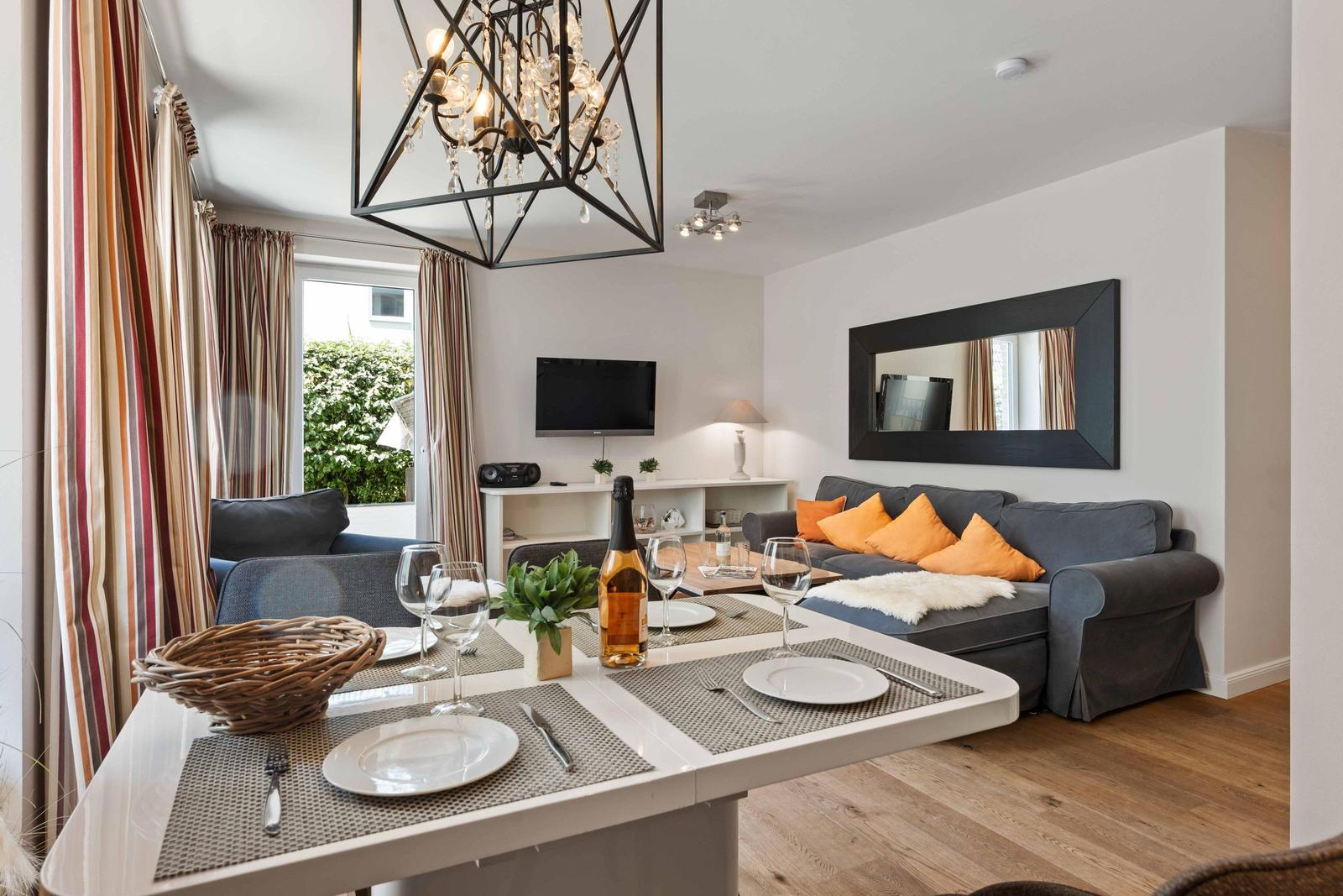 Dining area with table, chairs, and a sofa. Background: TV and mirror on the wall.