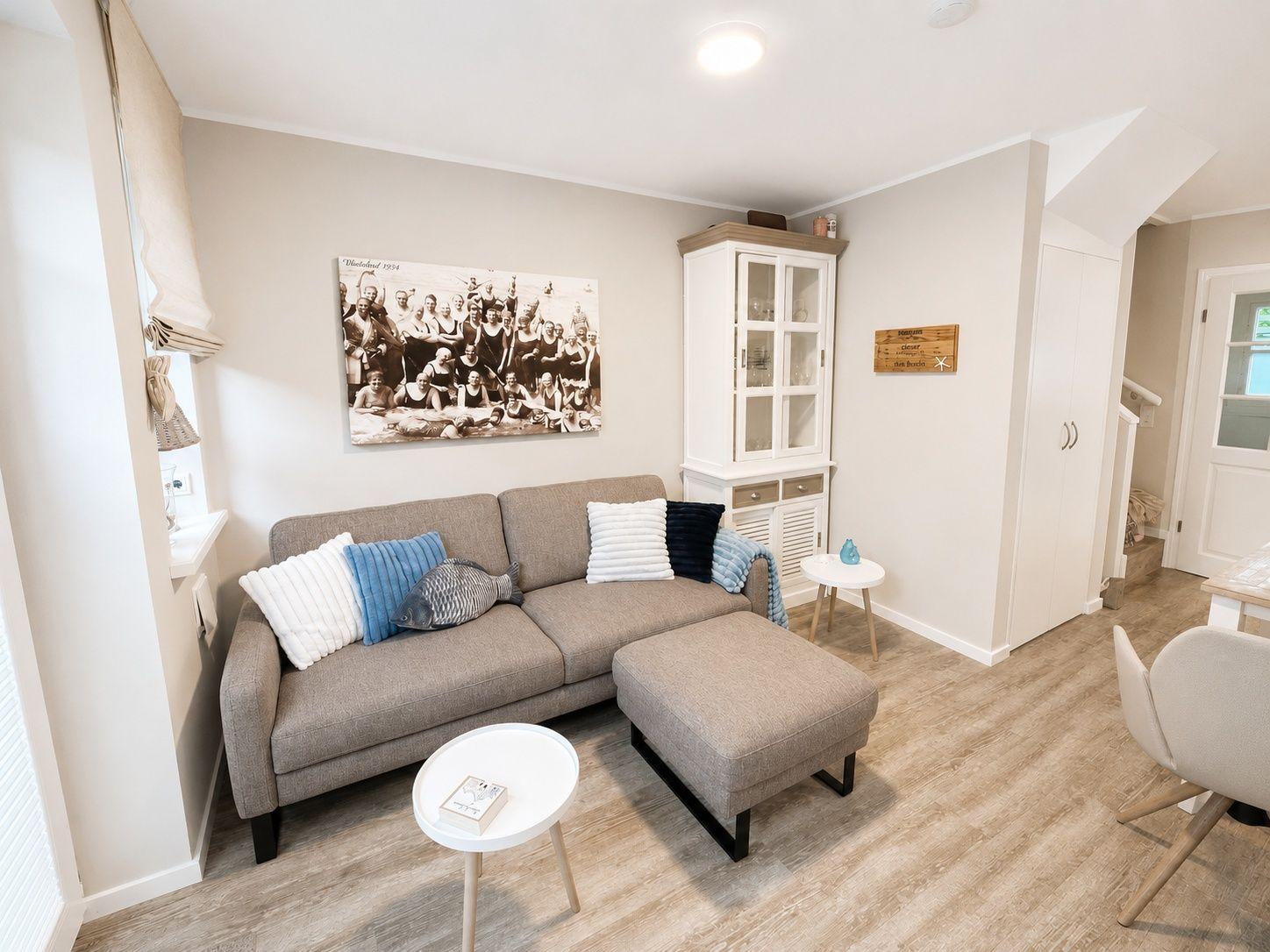 Wohnzimmer mit Sofa, Beistelltisch und Wandbild. Hölzerner Boden und weiße Möbel.