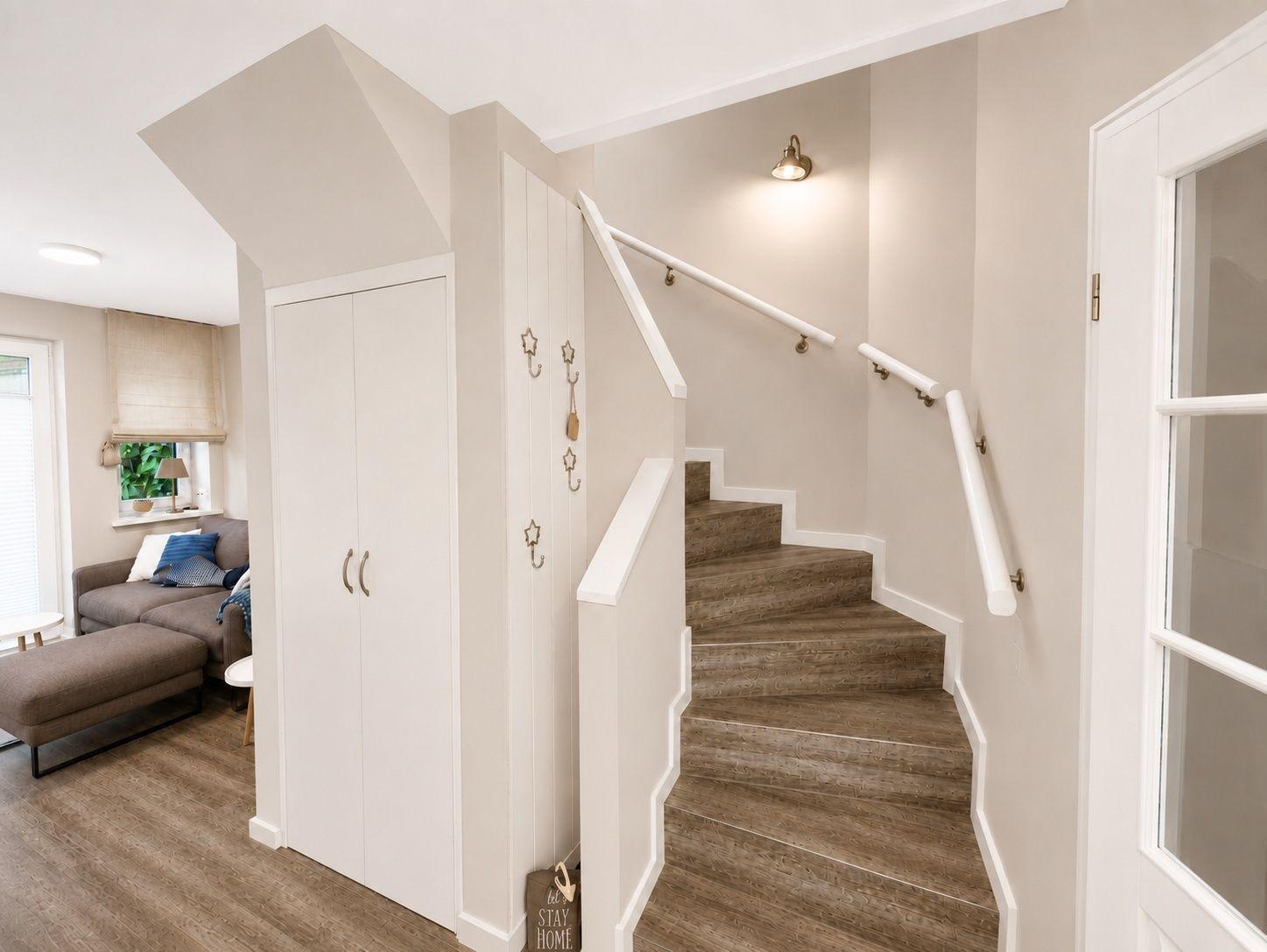 Treppe mit Handlauf führt zur oberen Etage. Nebenbei steht ein weißer Schrank.