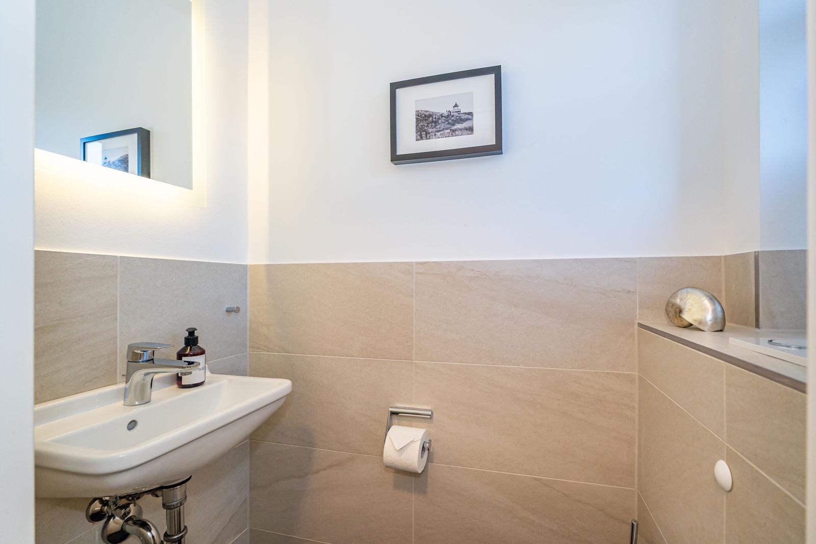 Badezimmer mit Waschbecken, Spiegel und Wandbild.