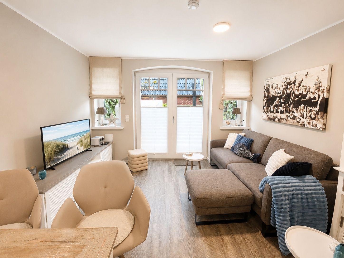 Wohnzimmer mit Sofa, Fernseher und Fenster zur Außenseite.