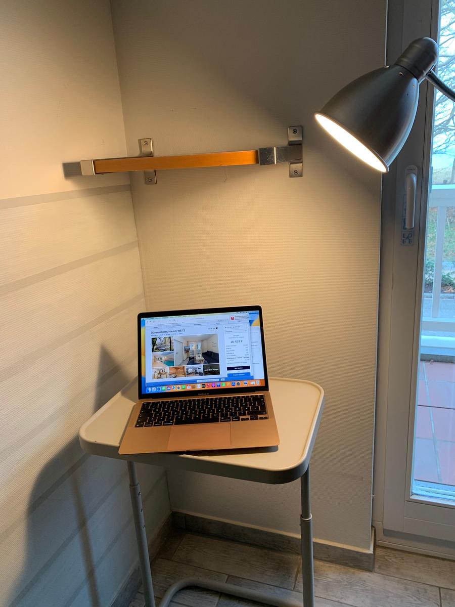 Laptop auf Schreibtisch mit Stehlampe und Blick auf Balkon