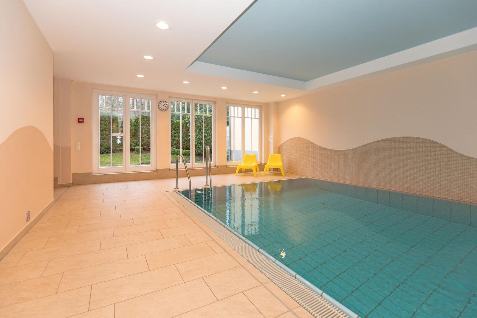 Innenpool mit gelben Stühlen und großen Fenstern zur Außenterrasse.