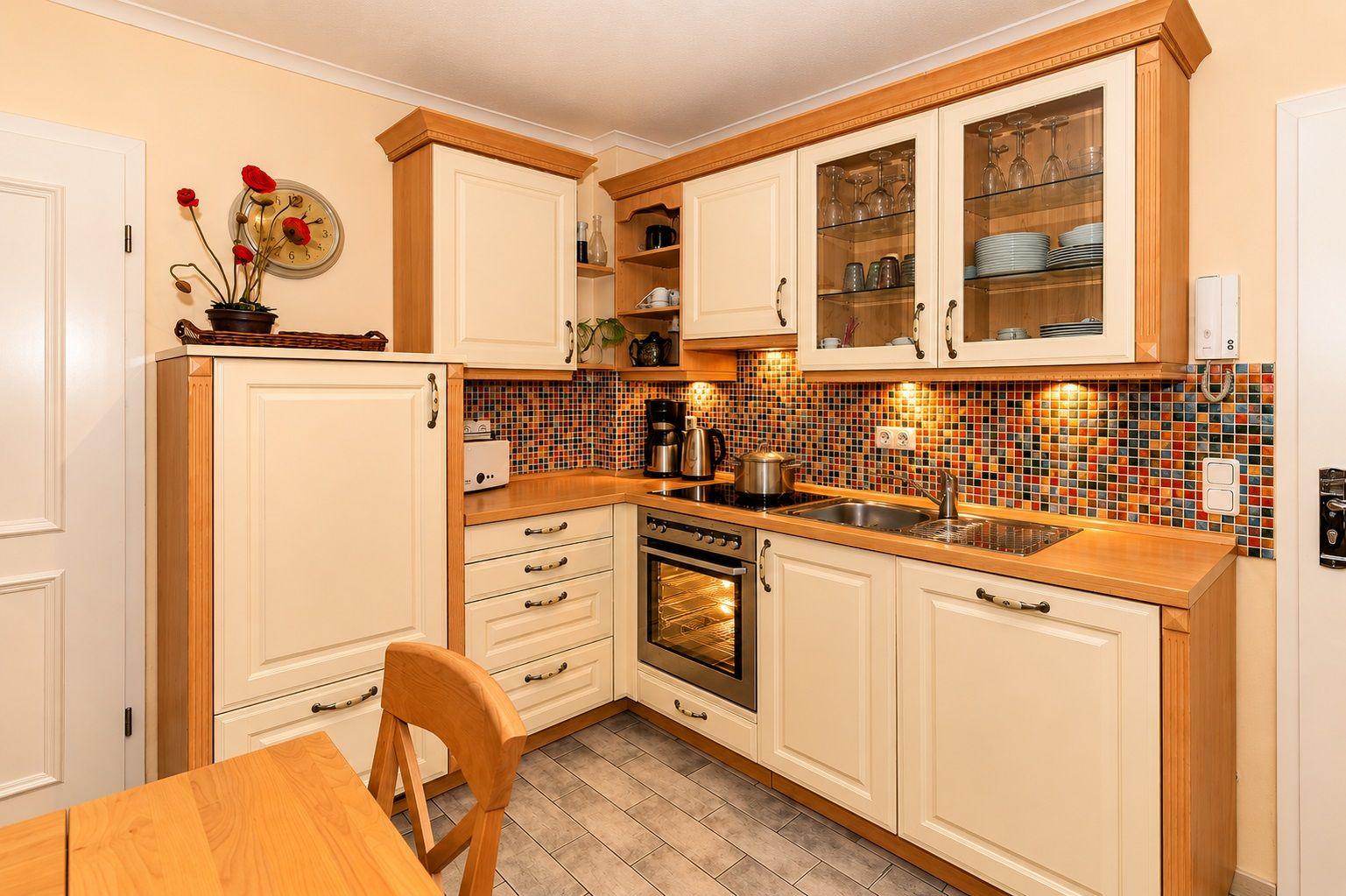 Küche mit Holzoberflächen, Glasfrontschrank und Mosaikwand