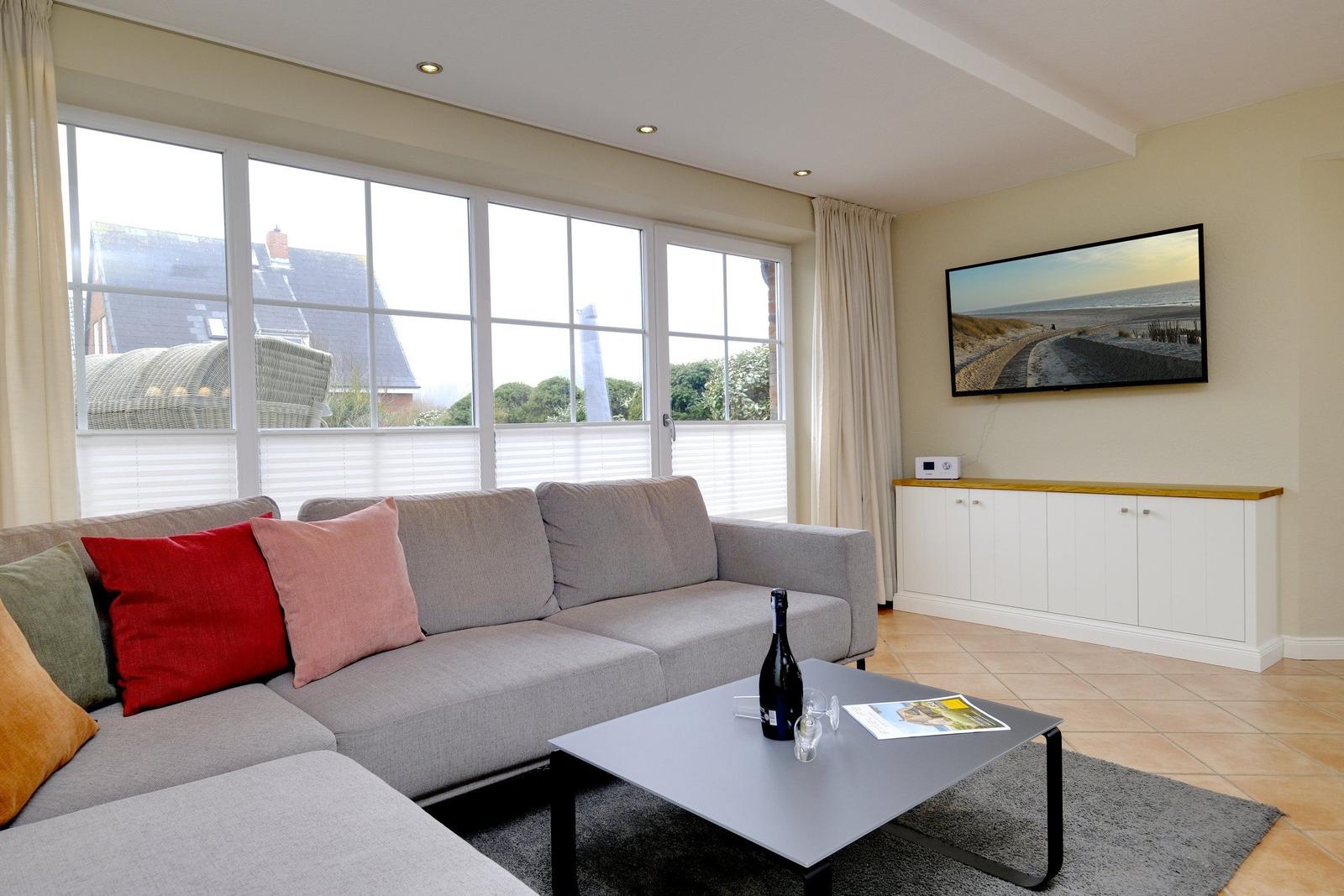 Wohnzimmer mit Sofa, Couchtisch und Fernseher an der Wand.