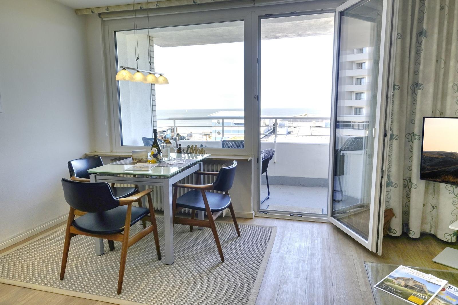 Essbereich mit Tisch und Stühlen, Balkon mit Meerblick und TV im Wohnbereich.