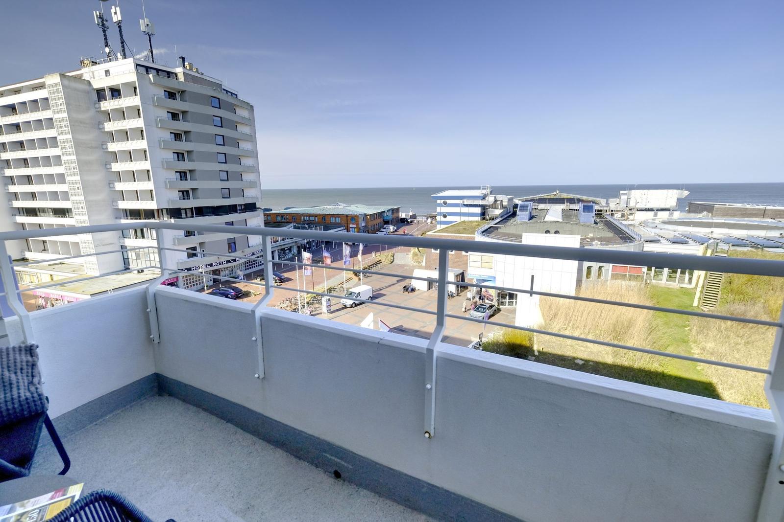 Terrasse mit Blick auf das Meer und Stadt. Graue Brüstung, Sitzgelegenheit.