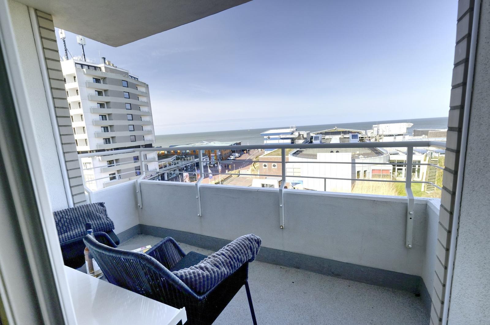 Balkon mit Sitzgelegenheit und Meerblick auf das Meer und Gebäude.