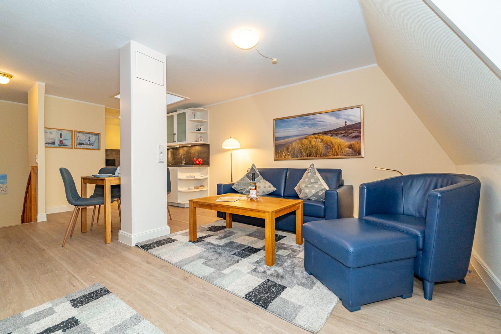 Wohnbereich mit blauer Couch, Holztisch und Bild an der Wand.