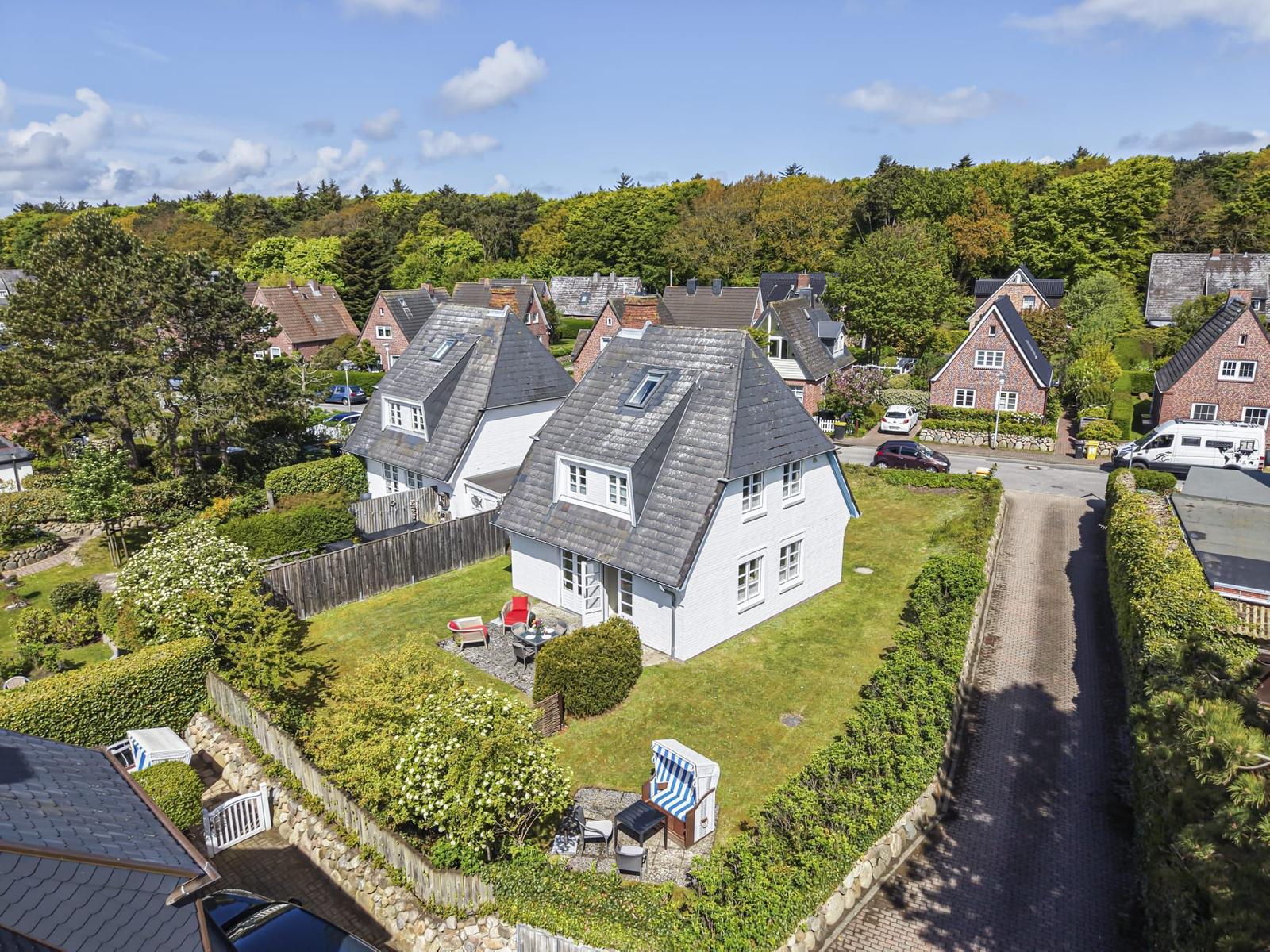 Wohnhaus mit Garten und Terrasse. Umgeben von Bäumen und Nachbarhäusern.