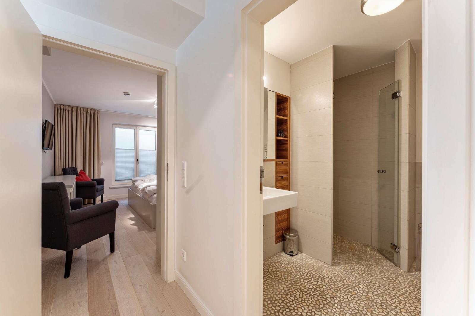 Bathroom with shower and sink. Bedroom with bed, chair, and window.