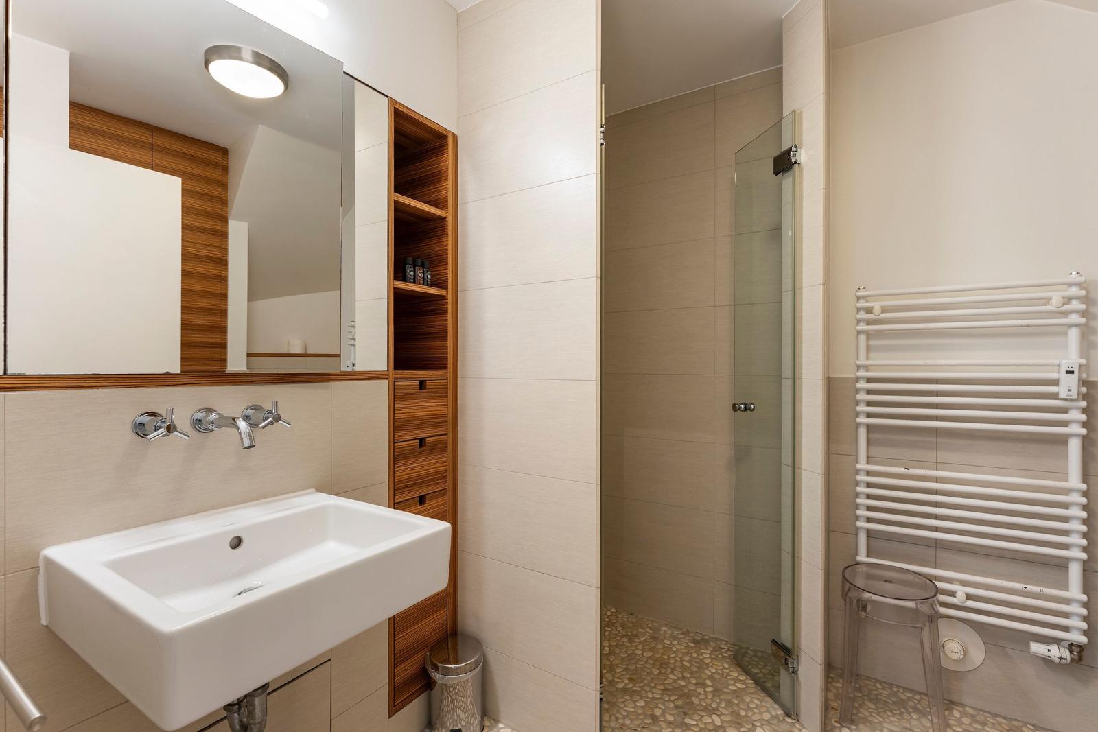 Bathroom with shower, sink, and towel heater