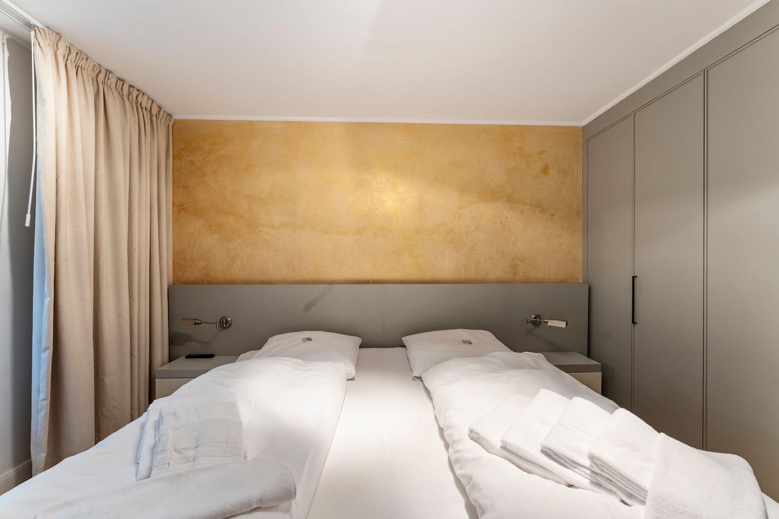 Bedroom with double bed, gold wall, and wardrobe.