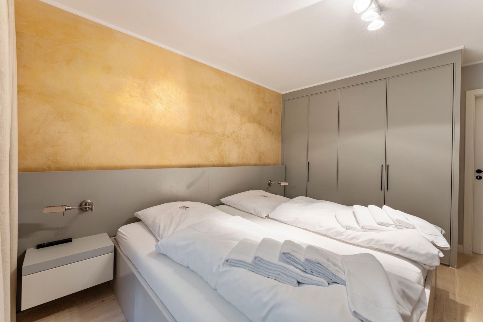 Bedroom with double bed, nightstand, and wardrobe against the wall.