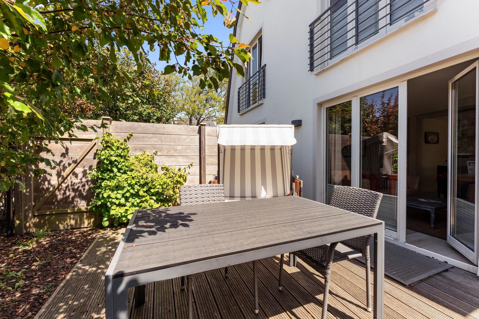 Terrace with table, chairs, and awning. Backyard with wooden fence and plants.