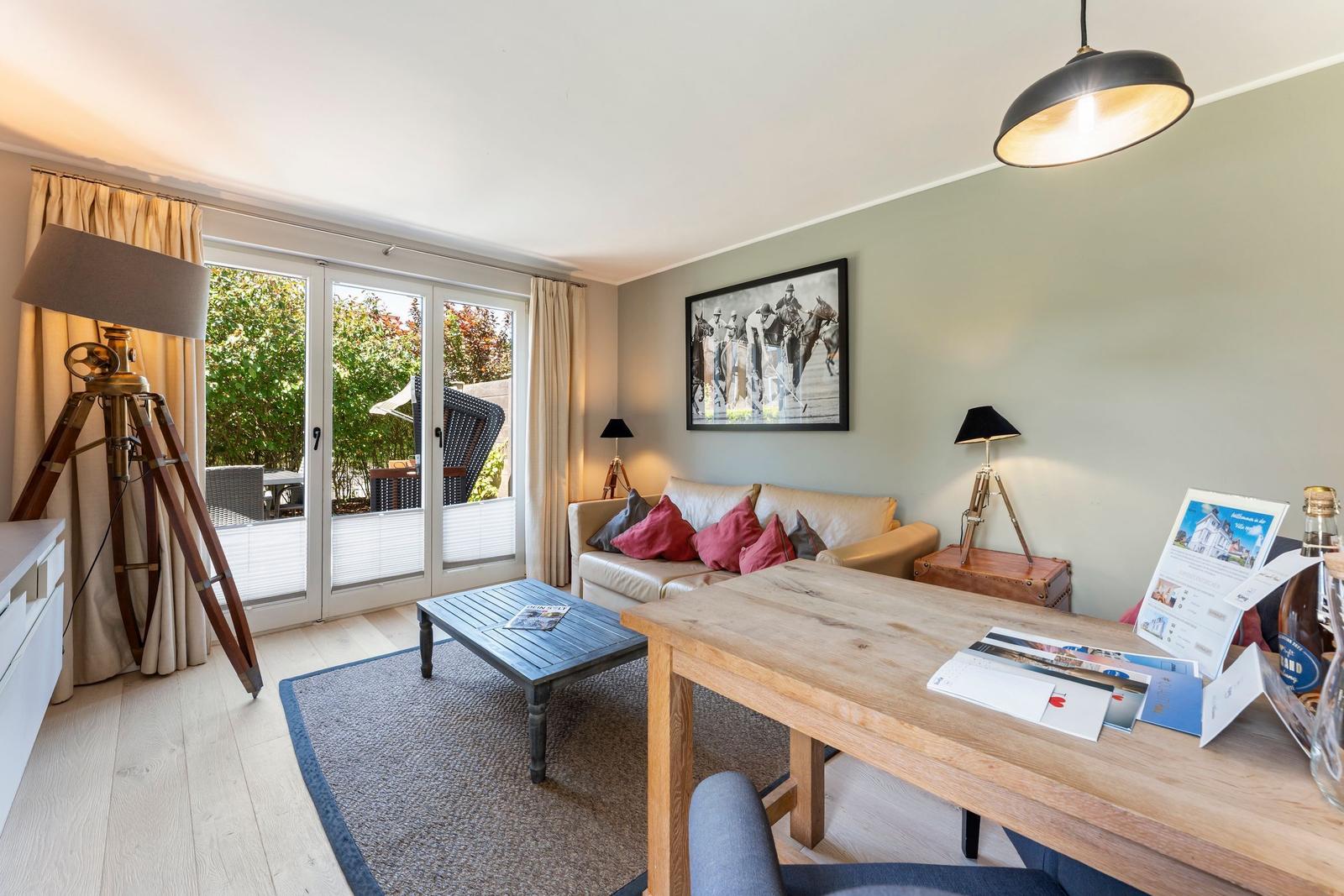 Living room with sofa, table, and view to balcony. Wall art and wooden furniture.