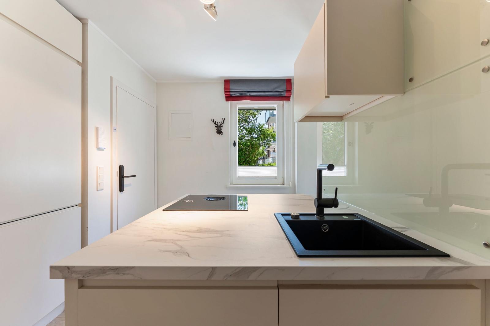 Kitchen with marble countertop, black sink, and window with view outside.