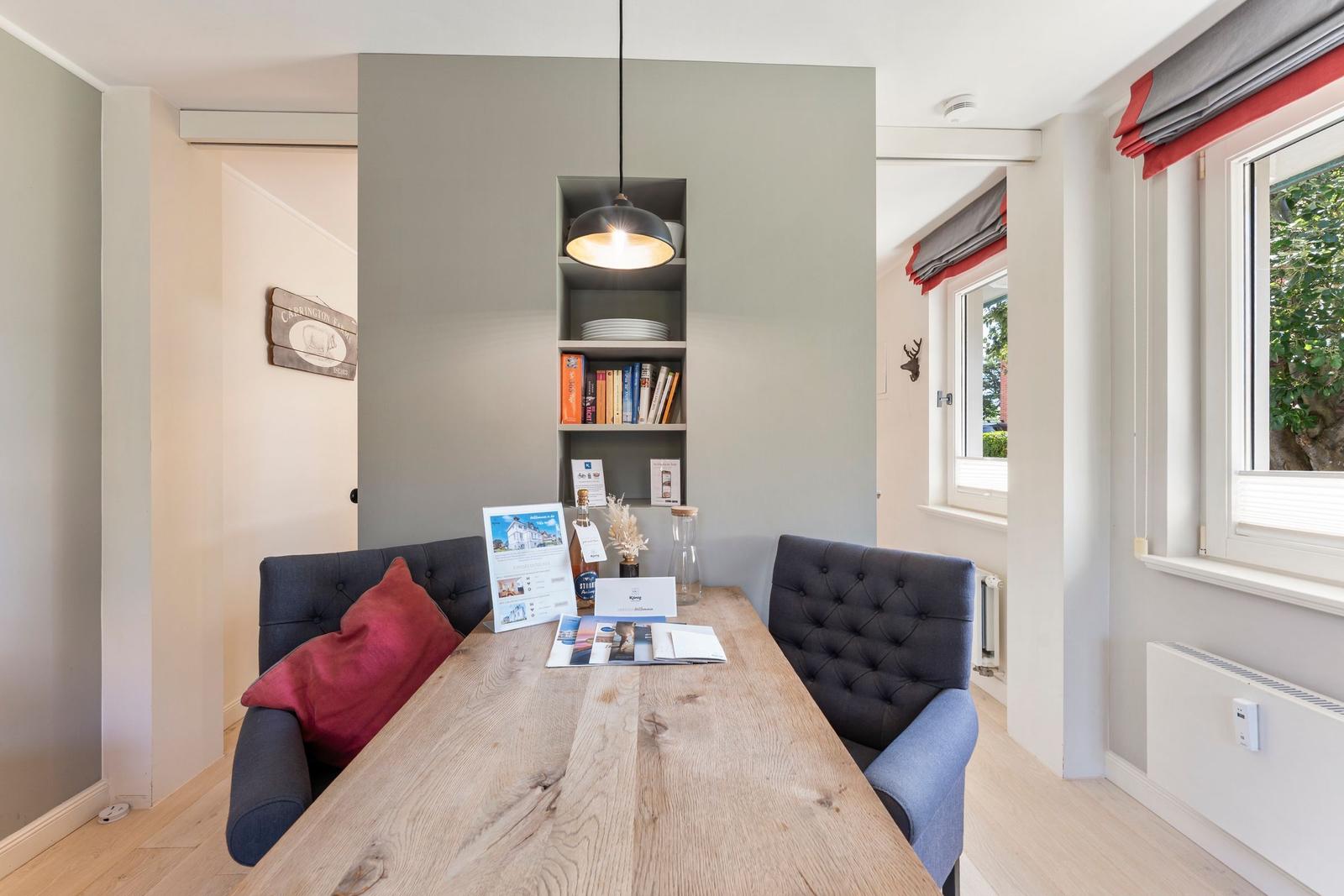Dining area with wooden table, dark blue chairs, and built-in wall shelving.