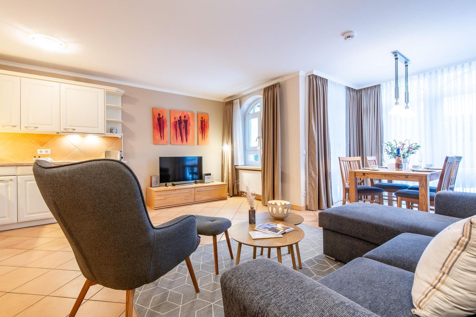Wohn- und Essbereich mit Küche, Sofa, Stuhl und Fernseher.
