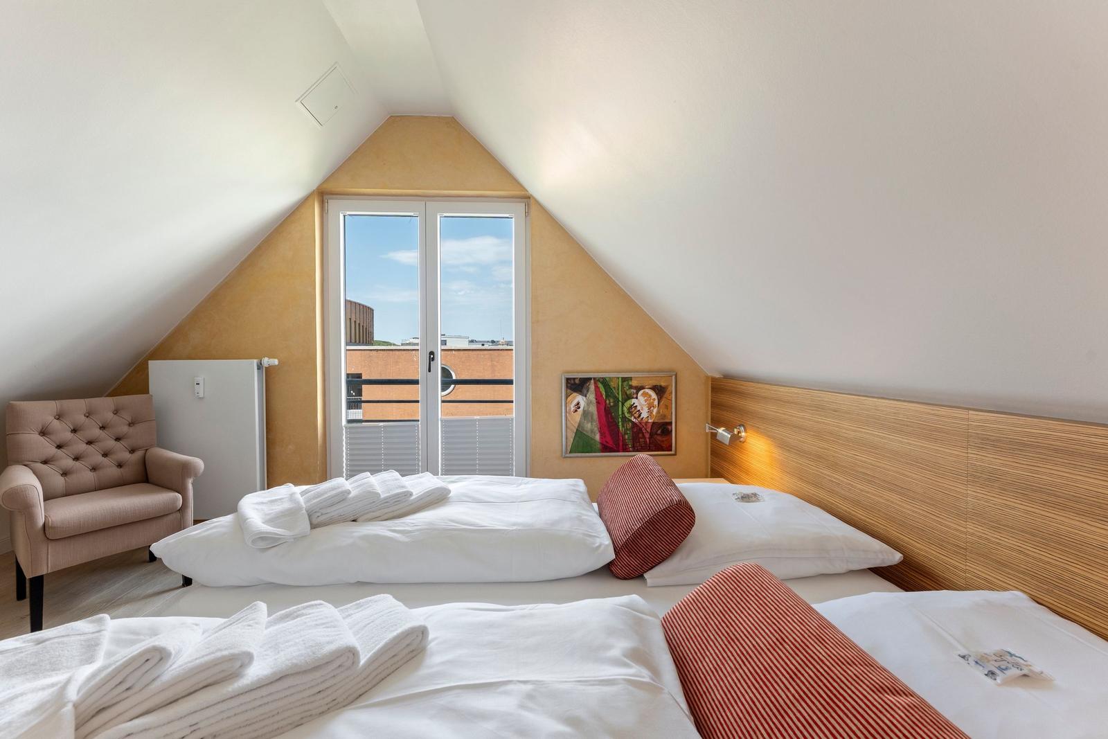 Zimmer mit Doppelbett, Sessel und Fenster zur Aussicht.