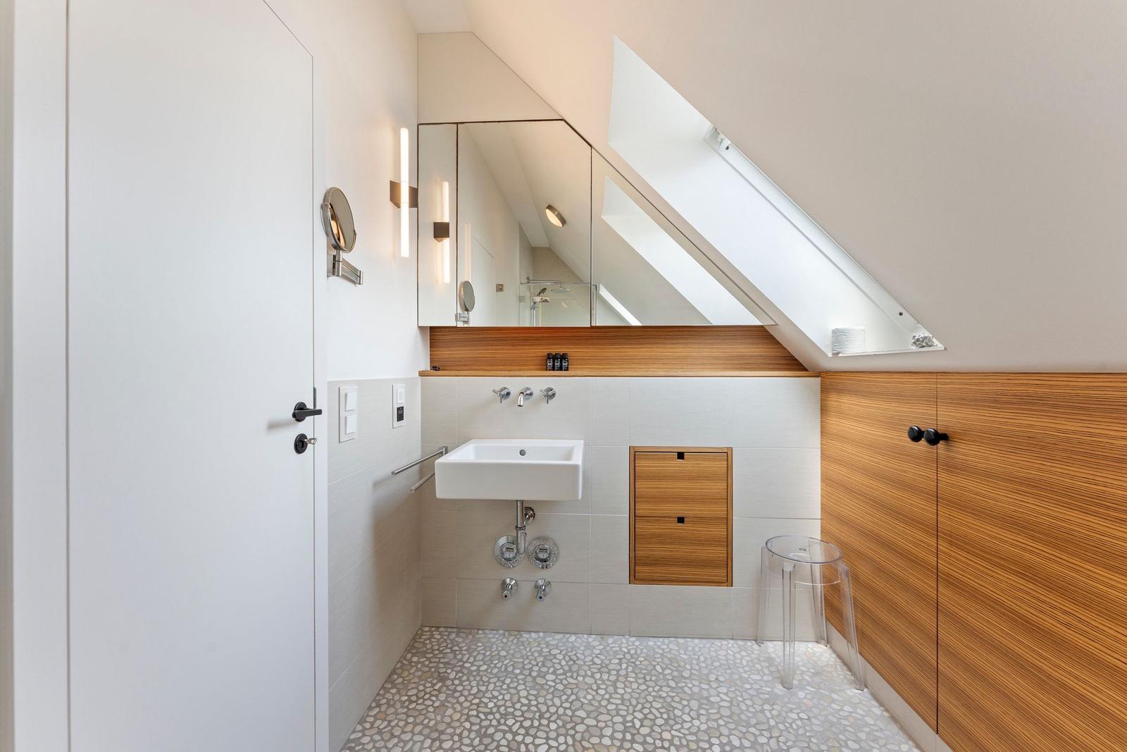Dusche mit Spiegel, Holzwand und Fenster unter Dachschräge