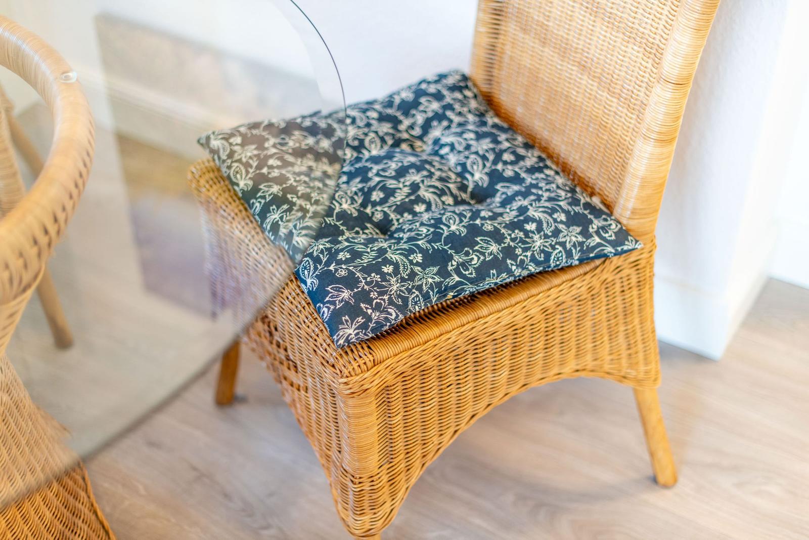 Rattan-Stuhl mit gemustertem Kissen auf Holzboden