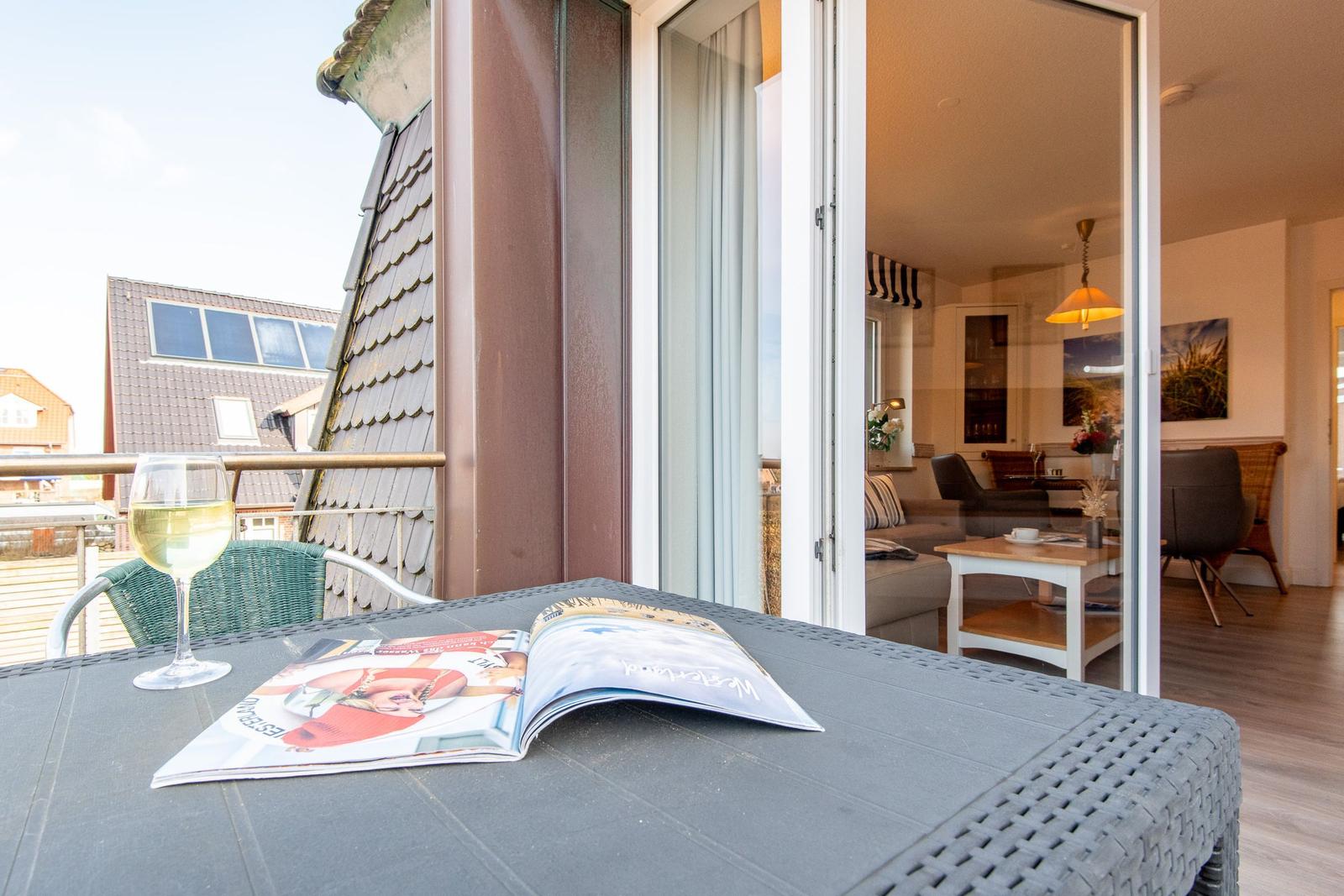 Terrasse mit Tisch, Stuhl und Wein. Blick ins Wohnzimmer mit Sofa und Tisch.