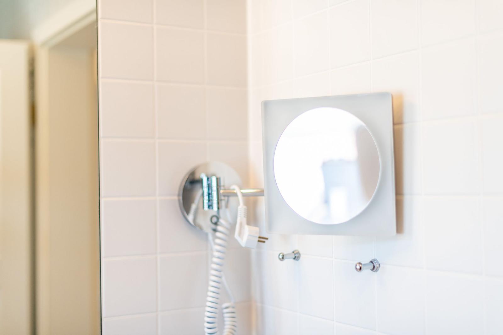 Badezimmer mit Spiegel und Duschkopf an der Wand