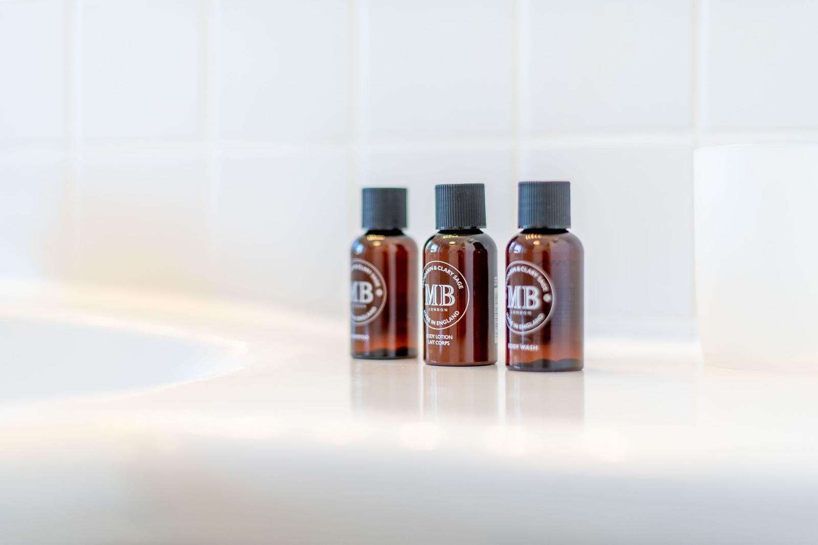 Drei kleine Flaschen mit Badprodukt auf einer weißen Oberfläche.