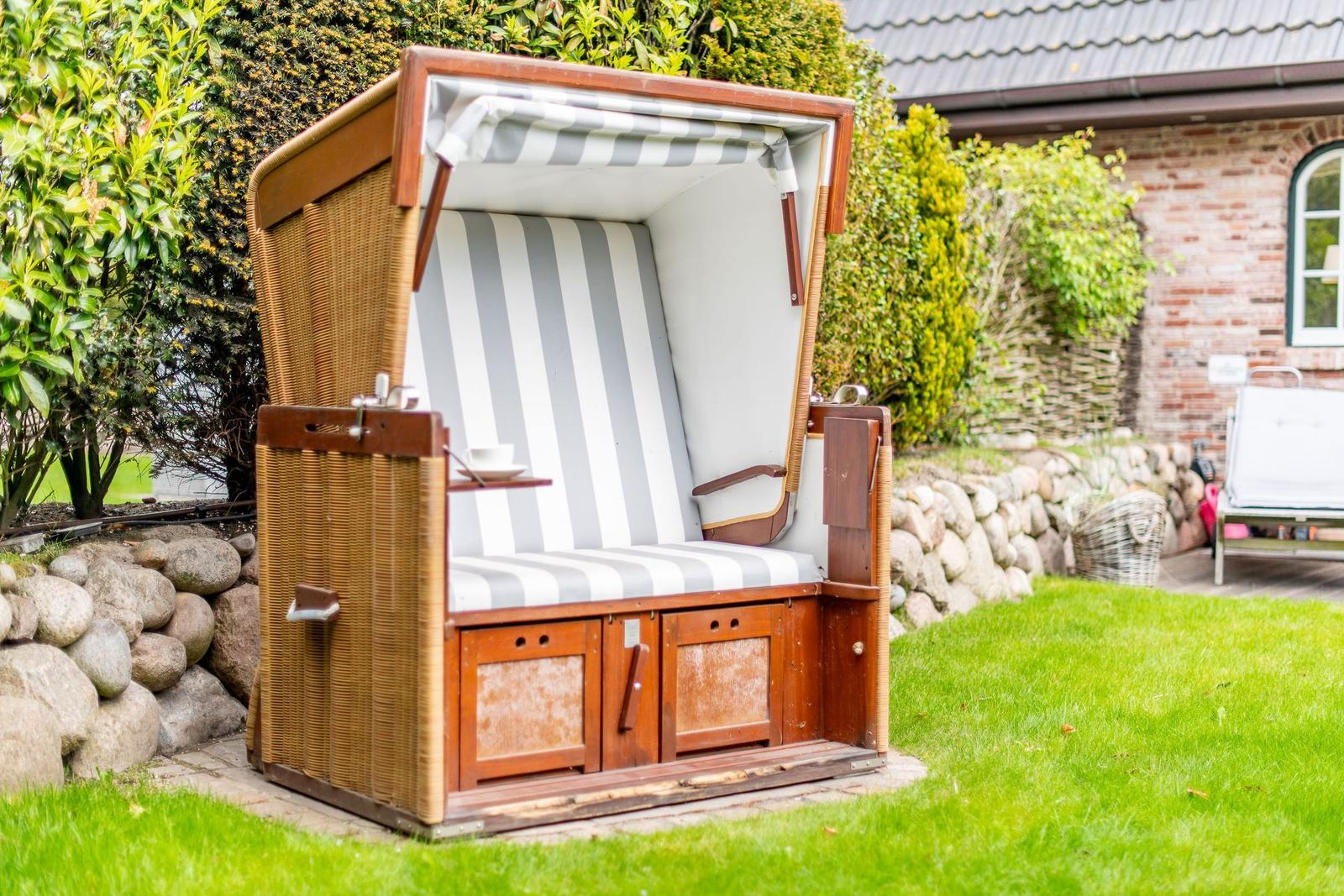A traditional beach chair with striped upholstery is in the garden.