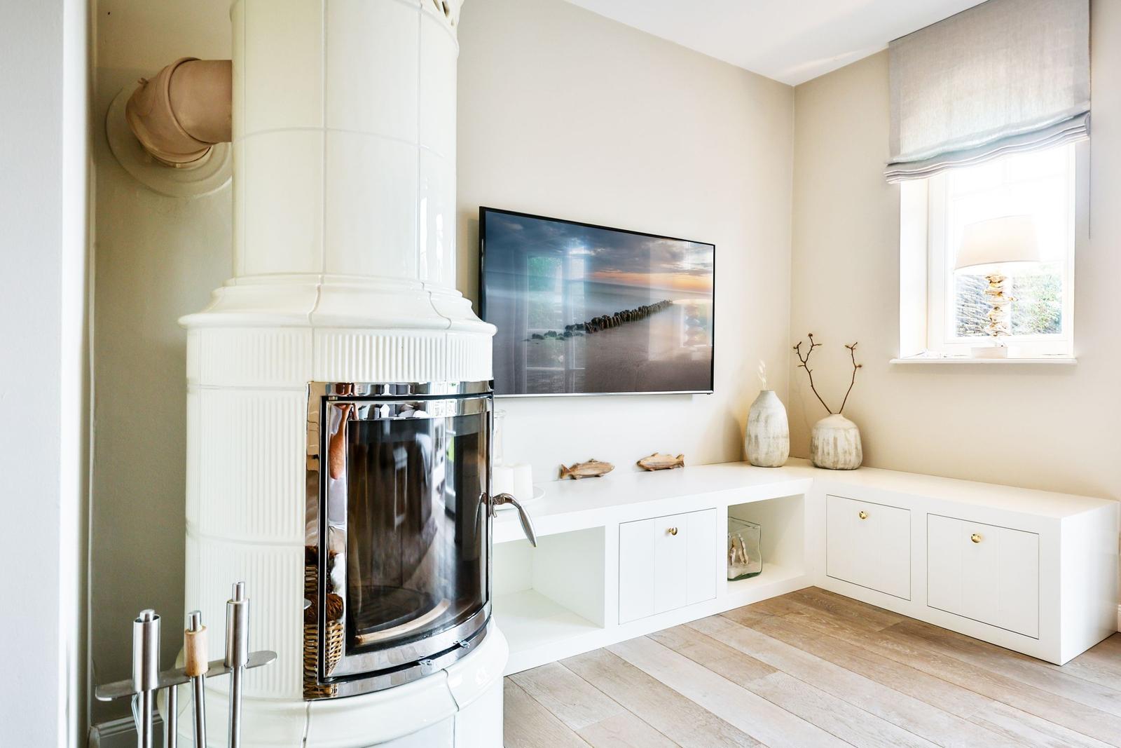 Living room with white fireplace, TV, and window with lamp.