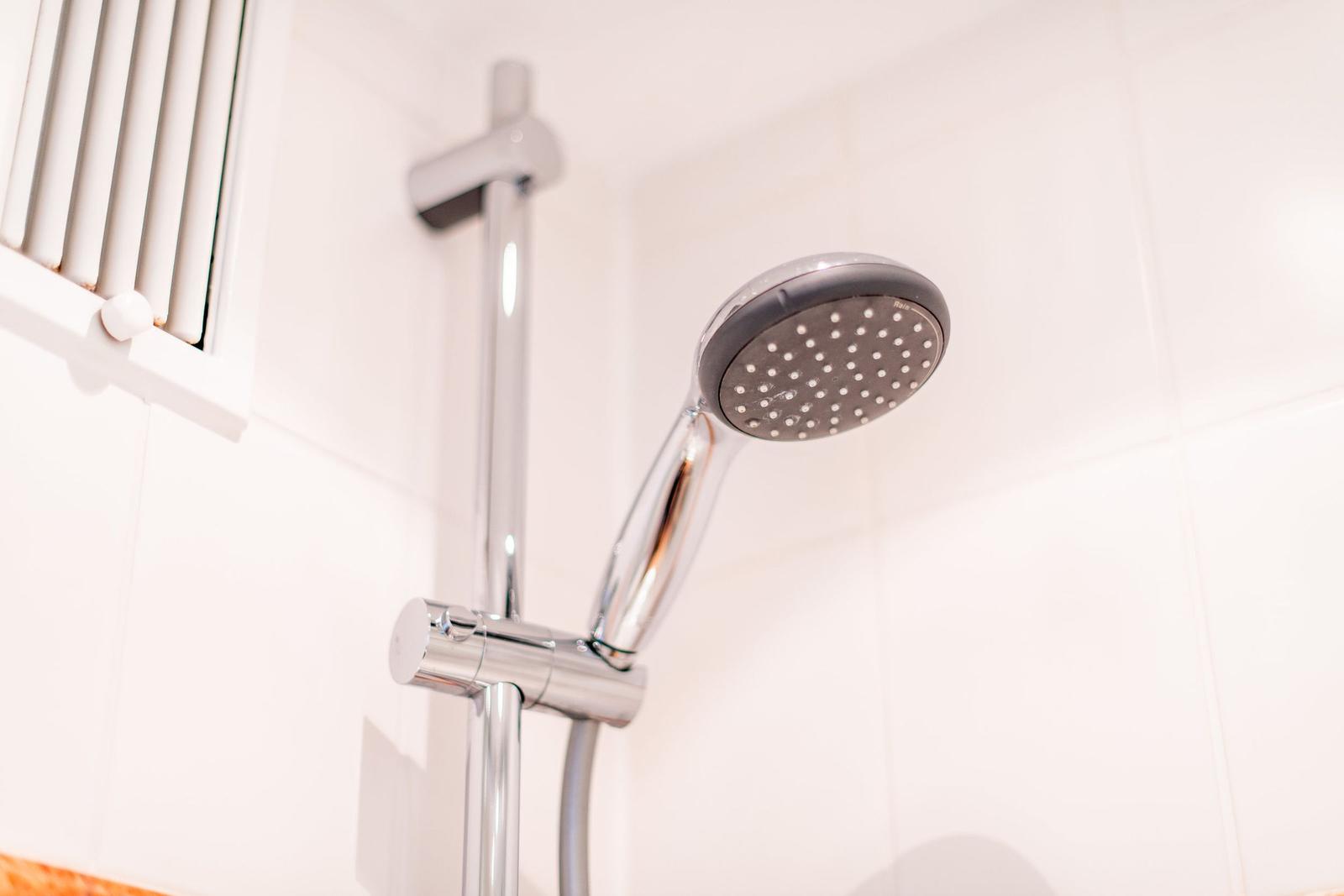 Duschkopf mit Handbrause und Duschstange an weißer Wand