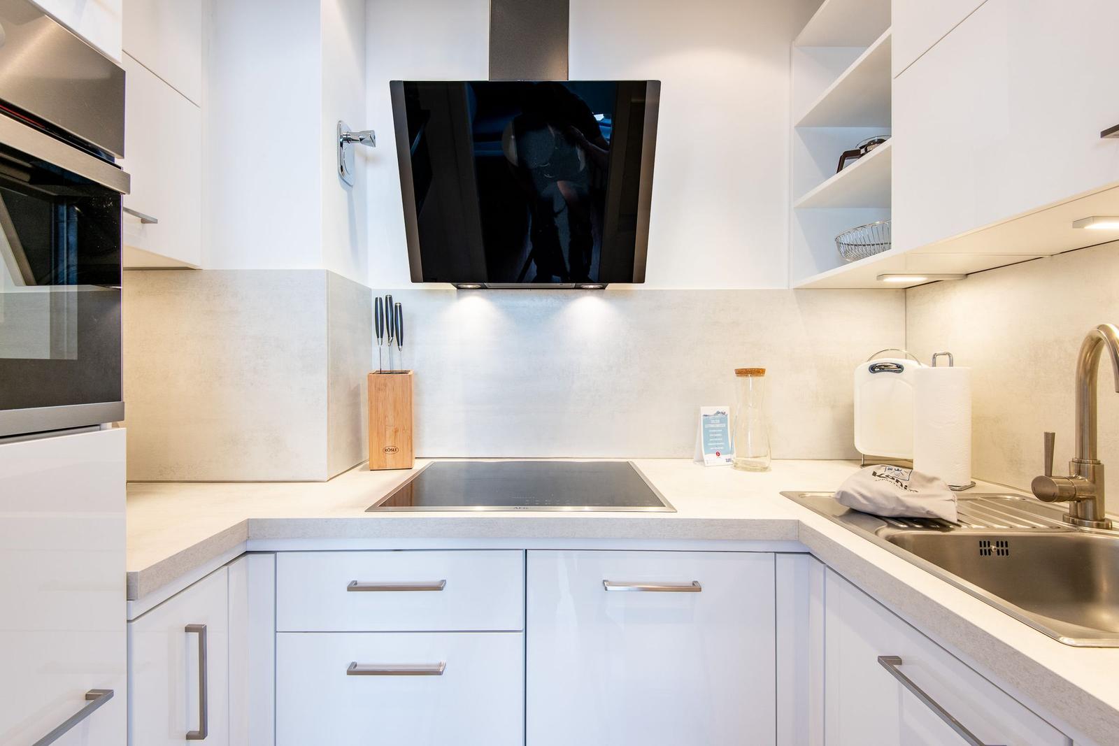 Moderne Küche mit Edelstahlspüle, Induktionskochfeld und integriertem Backofen.