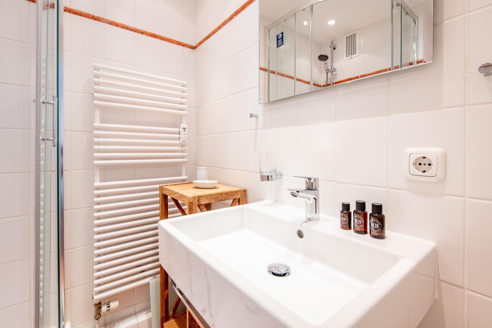 Badezimmer mit Waschbecken, Spiegel und Dusche