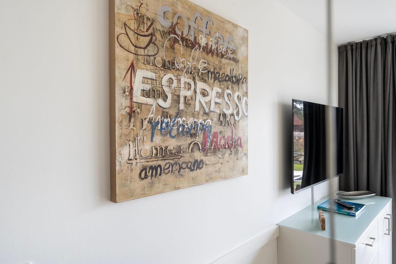 Wall art with coffee motifs, TV, and cabinet in the living area.