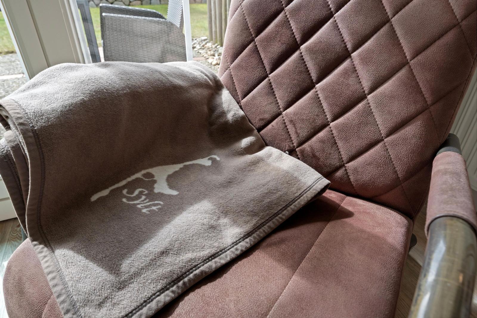 A brown seat with cushion and towel with logo.